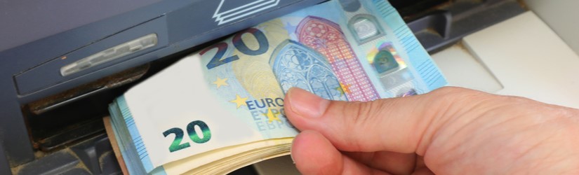 personne qui ramasse des billets européens de 20 euros dans un distributeur de billets de banque