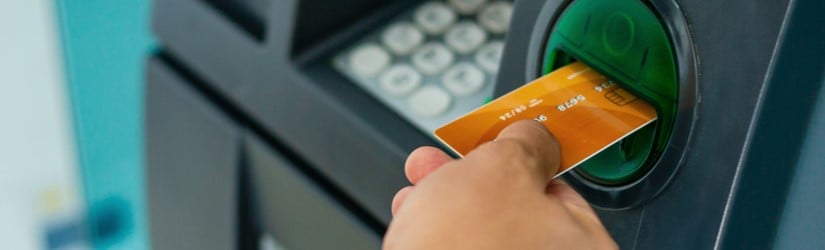 gros plan d'une main d'homme utilisant un distributeur automatique de billets pour retirer de l'argent