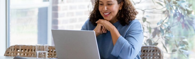 Une femme utilise un ordinateur portable tout en faisant visiter son compte en ligne, y compris boursobank