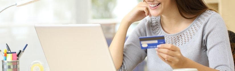 Femme heureuse payant avec une carte de crédit sur un ordinateur portable.