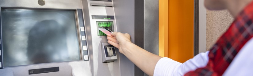 Femme utilisant un distributeur automatique de billets et une carte de crédit pour retirer de l'argent